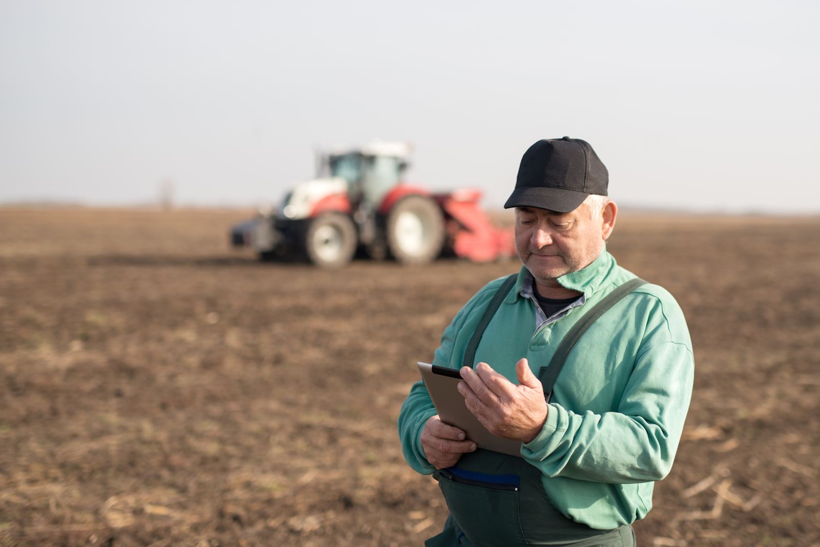 A farmer kneeling in his field, examining the crop