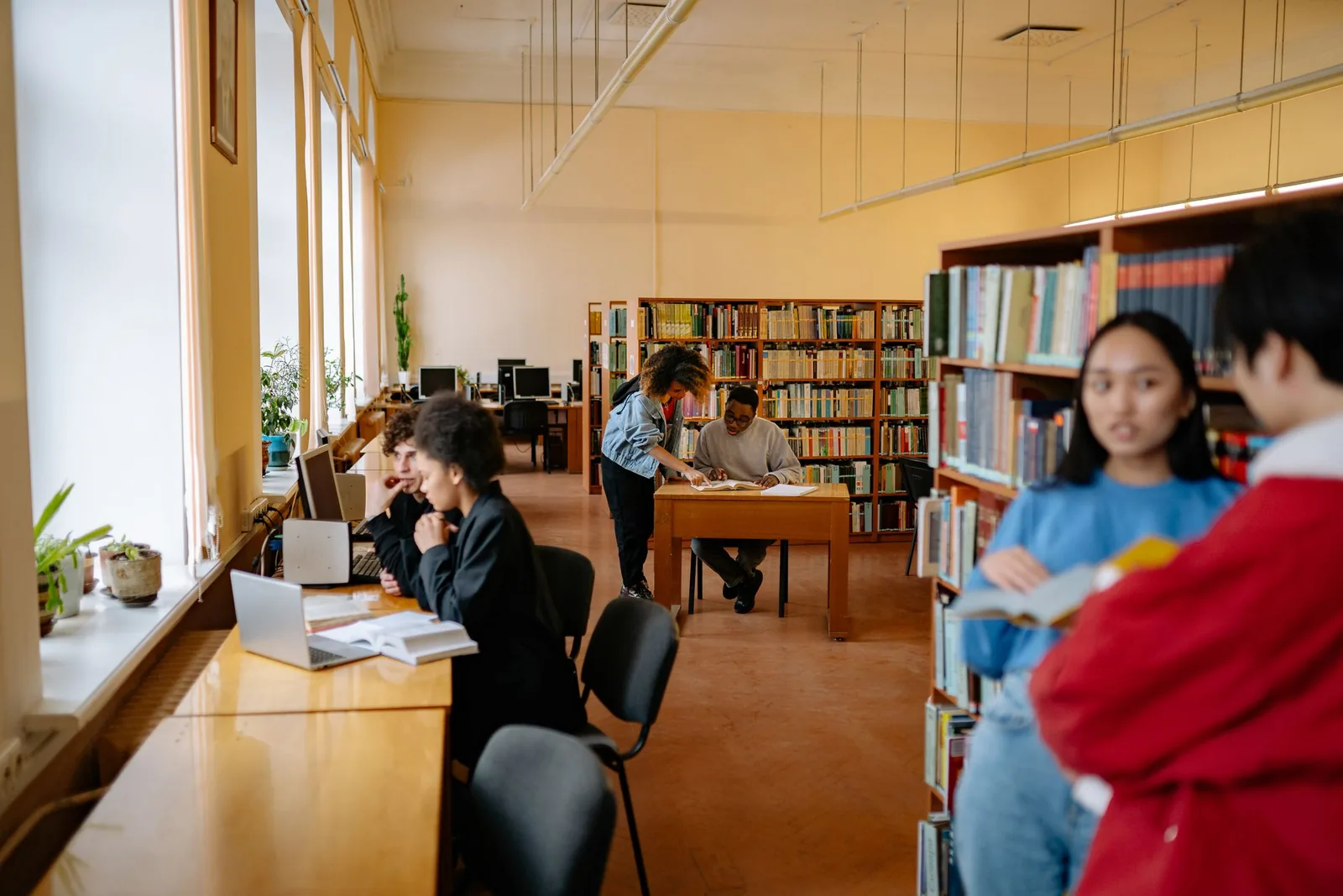 College students studying with books and laptops in a university library