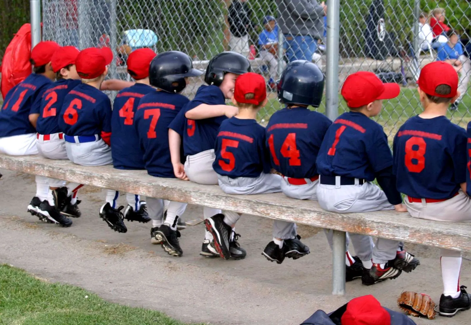 Young baseball teammates seated together beside a playing field