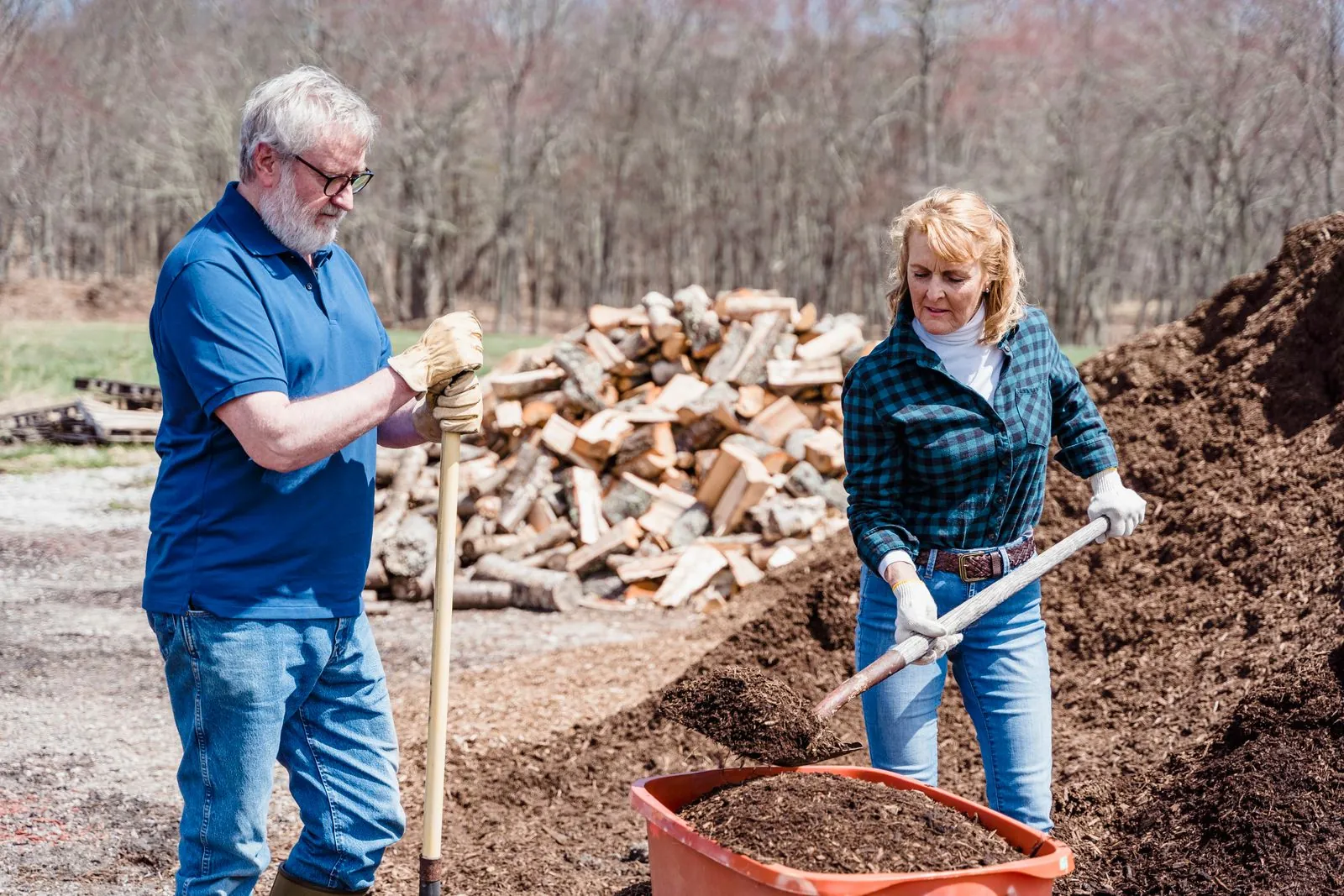 An older couple gardening together beside a woodpile